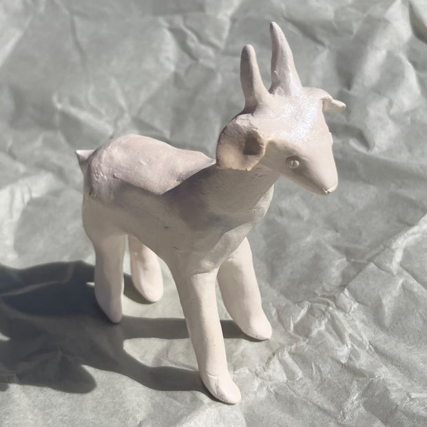 White ceramic goat figurine on a textured gray background