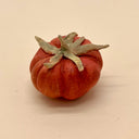 Small terracotta sculpture of an orange heirloom tomato with a green stem.