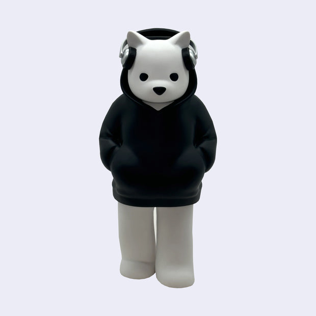 Vinyl figure of a white bear standing and wearing a black hooded jacket. He has on a pair of silver headphones and has his hands in his pockets.