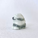 Ceramic sculpture of a sheep dog, sitting with its fur seemingly blowing in the wind, making it a slight blur with its eyes covered up.