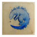 Illustration on mostly exposed wooden panel of a blue Godzilla character, sleeping on its side with its body in a C shape, its tail almost making contact with its face. A sparkle is between the points of contact and gold flakes dot the surface.