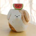 Clay sculpture of a round character, modeled to look like a dog without any arms or legs. Atop its head is an watermelon slice.