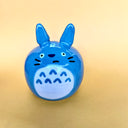 Ceramic sculpture of Totoro with a rounded body and a painted on cute face. His ears jut out from his head.
