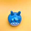 Ceramic sculpture of Totoro with a rounded body and a painted on cute face. His ears jut out from his head.