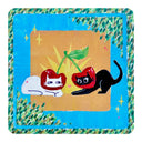 Illustration of 2 cats, one white and one black with cherry hood hats around their heads. The white one sits and the black one leans down on its front paws. Background is gold color block, surrounded by blue and green leaf shapes.
