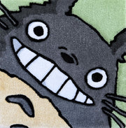 Tufted rug of Totoro, smiling and seen close up - only his face - with a mint green background.