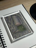 Illustration of a character in a green outfit standing among tall, cylindrical plants. It has a hood hat of the same cylindric shape.