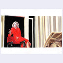 Painting of a woman in a red dress, sitting on the arm of a chair with a wine glass and a cigarette.