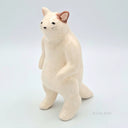 White ceramic cat figurine on a light gray background