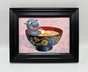 Framed artwork of a baby hippo in a cartoon style sitting in a bowl of miso soup.