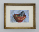 A whimsical illustration of a gray Godzilla-like dog monster sitting in a red bowl of ramen with gold bamboo motifs, set against a light blue background patterned with gray Godzilla silhouettes. Framed in a gold frame.