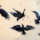 Illustration of black birds on a beige ceramic plate with blue specks