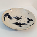 Ceramic plate with black bird illustrations on a white background