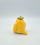 Yellow bird figurine with a green leaf hat on a white background
