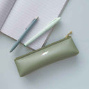Green pencil case with a pen and notebook on a light surface