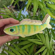 A hand holds a 5.5" long illustration of a green fish. It has striping down its body, large blue eyes, a wavy top fin, and a friendly, excited smile. 