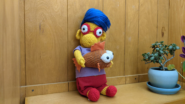 Crocheted sculpture of Millhouse from The Simpsons holding Blinky the three eyed fish.