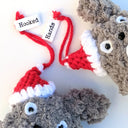 Close up of crocheted Totoro ornaments, with small red Santa hats hanging on one of their ears.