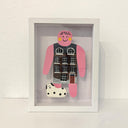 Paper cut out of a person wearing a shirt that resembles a building. Sitting at her feet is a black and white dog.