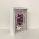 Paper cut out of a person wearing a shirt that resembles a building. Sitting at her feet is a black and white dog.