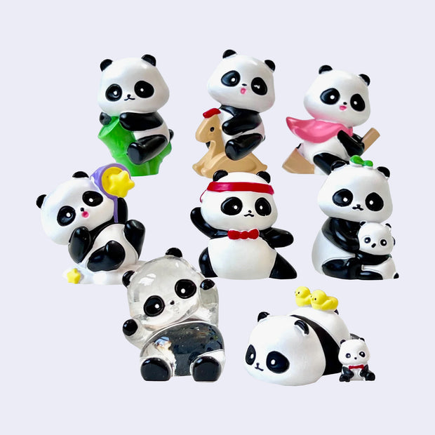 8 different small figurine designs of panda, with one of them clear with painted accents. They are in various positions and poses interacting with different objects.