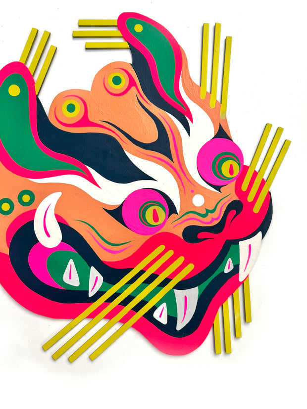 Die cut painted wooden panel of a old Asian style tiger dragon, similar to one in a parade. It is very colorfully painted (orange, pink, green, red) and has sharp curved teeth and yellow lined hair on the sides of its head. Close up.