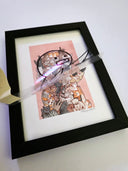 Framed artwork of a mound of cats, forming the shape of a person. Atop it is a clear sheet with a marker line drawing of a person, which is being lifted up partially.