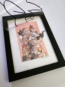 Framed artwork of a pile of cats against a white background. A clear sheet with a marker illustration of a character is superimposed on top, but being lifted up.