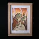 Framed artwork of a green creature with butterflies against a cityscape background