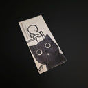 A rectangular drawing of a black-and-white cartoon illustration of a child at a desk and a large cat face, photographed on a dark black background. Visible text includes 'POST EXPRESS MAIL' and 'POST EXPRESS MAIL POST'.