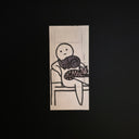 A rectangular drawing of a minimalist black ink illustration of a stick-figure-like figure holding a cat, photographed on a dark black background.