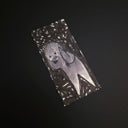 A drawing featuring a stylized gray and white illustration of a ghost-like figure, photographed on a dark black background.