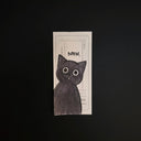 A rectangular black cat illustration with large white eyes, placed on a dark black background. The card has a white border and partial text including 'MEH.'