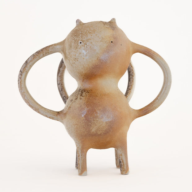 Brown ceramic sculpture of a character with a rounded body, small eyes and ears and mug handle like shapes coming out of its sides and back.