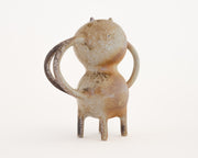 Brown ceramic sculpture of a character with a rounded body, small eyes and ears and mug handle like shapes coming out of its sides and back.