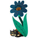 A stylized decorative illustration of a large blue flower with green leaves and stems, and a small black-and-orange cat peeking out from beneath the leaves, on a plain white background.