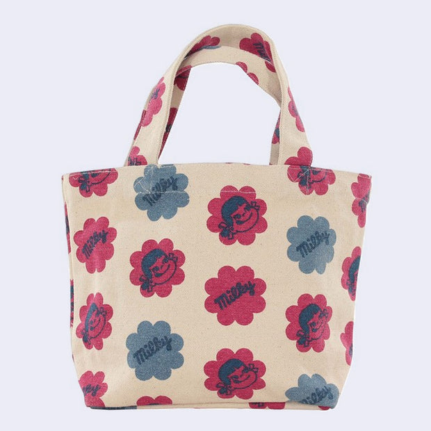 Cream colored purse with a pattern of large flower shaped blocks of red and blue, faded stylistically. One diagonal row features illustrations of Peko Chan's smiling face, and the next row features text that reads "Milky" within the flowers. Row pattern alternates between designs.