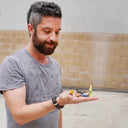 Man holding small figurines in front of a wall