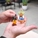 Hand holding small figurines of a campfire, dog, cowboy resting against a cactus and a black coyote or dog.