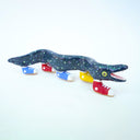 Ceramic sculpture of a blue eel with small, colorful polkadots and an open mouth with tiny teeth. The eel has 5 feet, all wearing sneakers either blue, red or yellow.