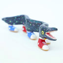 Ceramic sculpture of a blue eel with small, colorful polkadots and an open mouth with tiny teeth. The eel has 5 feet, all wearing sneakers either blue, red or yellow.