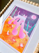 Risograph print of a pink and white cat with giant paws and very large legs, seen from slightly under. It walks on orange ground with tiny characters running alongside it.