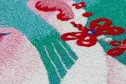 Embroidered illustration of the close up of a woman's ear. She has teal hair with straight bangs and wears a long, ornate red tassel earring. Her skin has pinkish tones. Side picture to show detail.