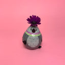 Small ceramic figure of a rounded, chubby gray bird with flowers coming out the top of its head.