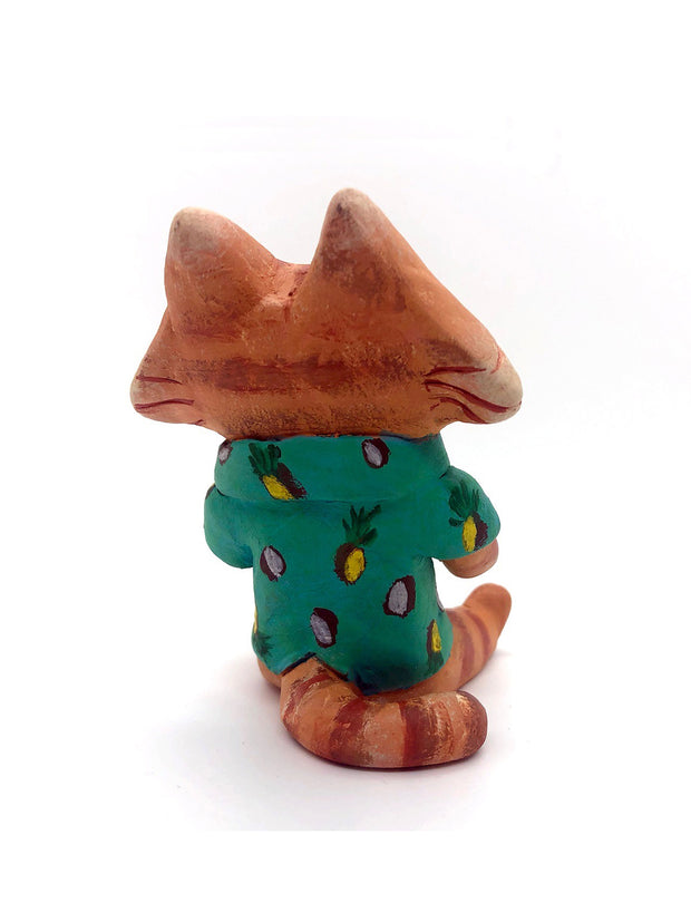 Sculpture of a cartoon style orange tabby cat, sitting with its legs out in front and eyes closed. It holds a pińa colada in its paws and wears a Hawaiian shirt. Viewed from the back.