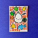 Artwork featuring a colorful cartoon illustration of a rabbit surrounded by vegetables, fruits, and chicks on a red-and-white checkered background, displayed on a textured blue surface.