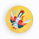 Painting on a yellow rounded wood panel of a bird, white and red wings. It is angled downwards with a star and a moon to the side of it.