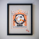 Ink illustration with orange color accents of a large cat wearing a black baseball cap and holding 2 dolls, one is a daikon creature and the other is a robot. It plays in front of a mini town with GR1 at GR2 and small dolls of the staff. Piece is elaborately framed like a play or theater.