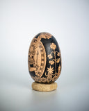 A hand-painted wooden egg with a detailed illustration of a cat holding a candle, with a sun overhead and within a nice border.