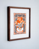 A stylized illustration of a white cat wearing a striped shirt and fabric collar, with a butterfly flying across its face, set against an orange and black theatrical curtain background with decorative border motifs including stars, hearts, and swirls. Piece is housed in wooden frame.
